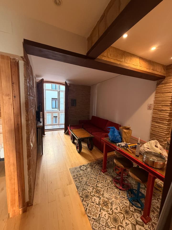 Salón reformado con ladrillo visto, vigas de madera restauradas y sofá rojo